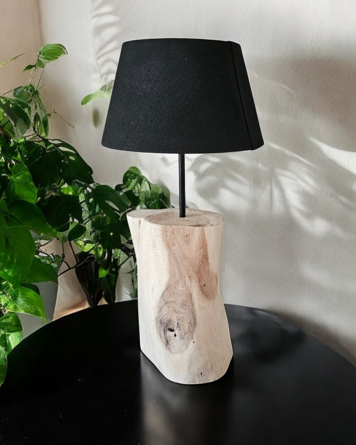 Houten boomstamlamp met zwarte kap op een tafel