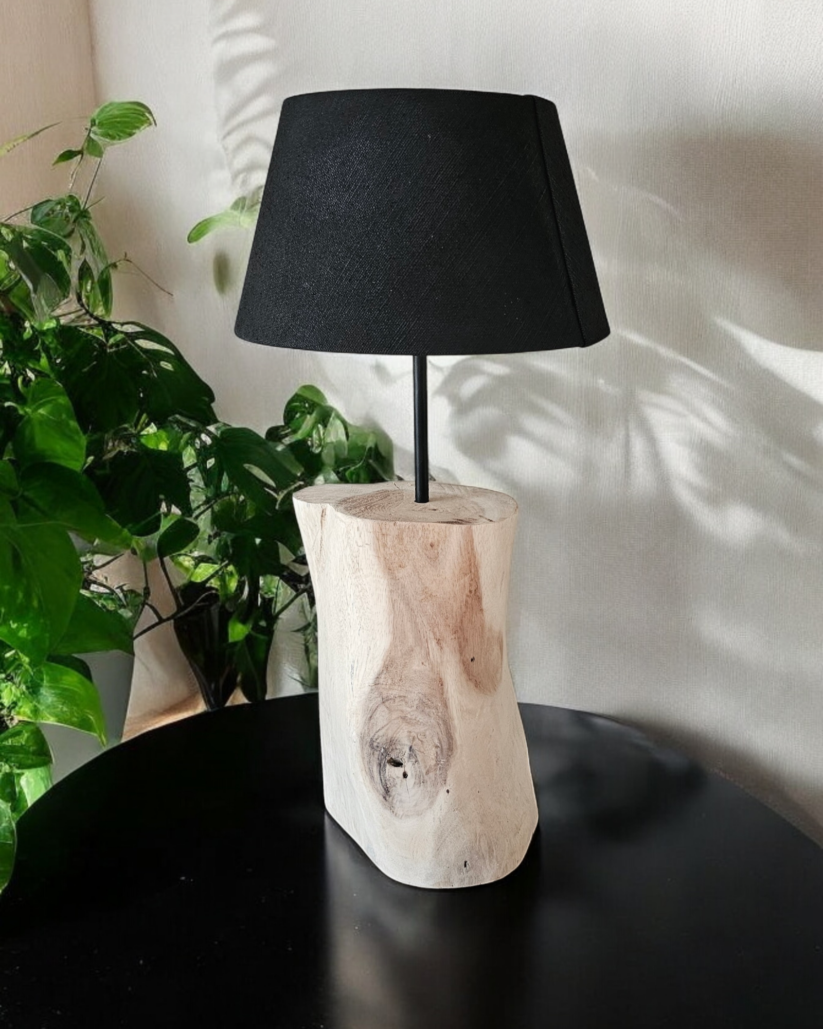 Houten boomstamlamp met zwarte kap op een tafel