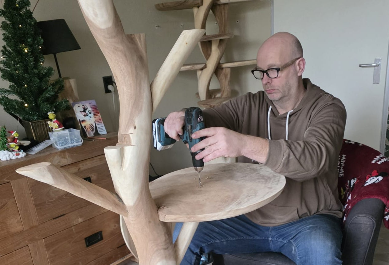 Man aan het werk aan een houten krabpaal met een boormachine