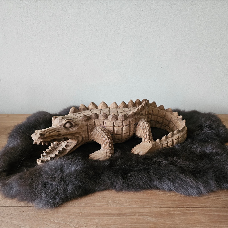 handgemaakt houten beeldje van een alligator op een kleedje